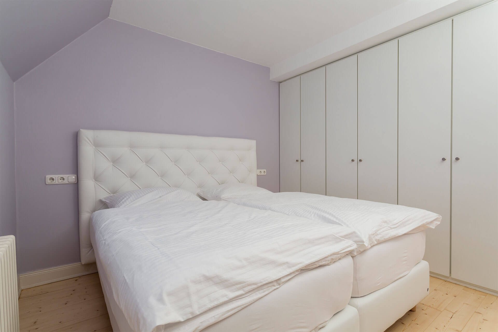 Das Schlafzimmer mit Boxspringbett mit frischer Betwäsche bezogen und Einbauschrank